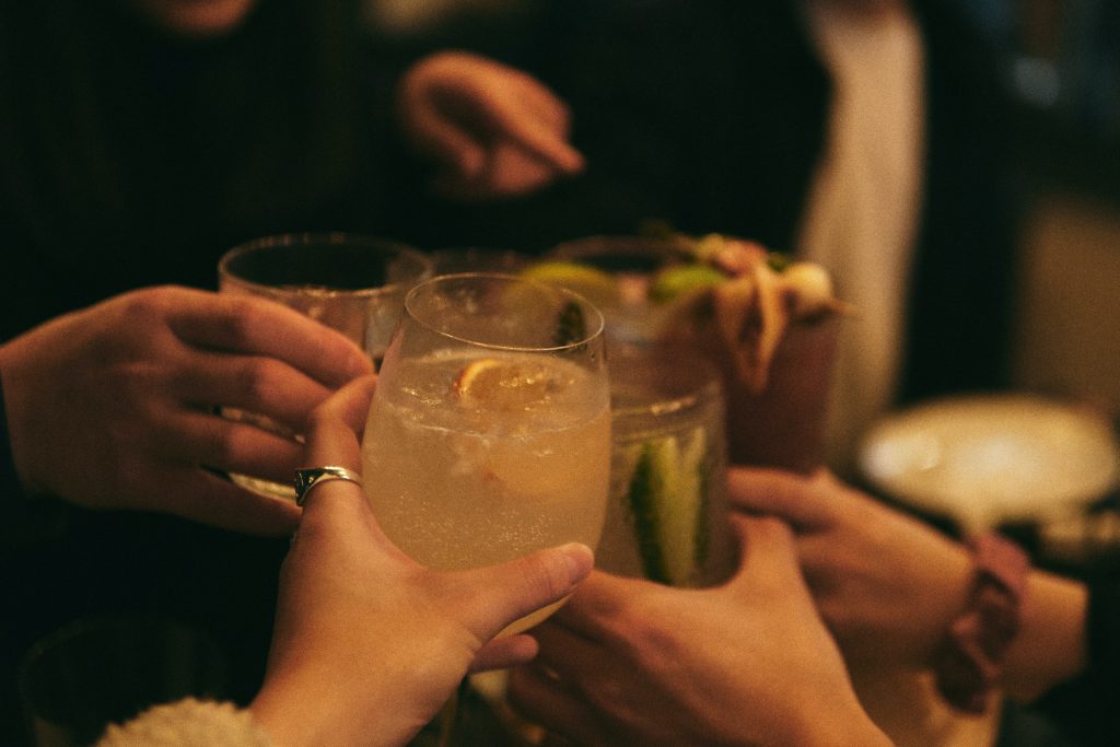 A variety of glasses with drinks being clinked together.