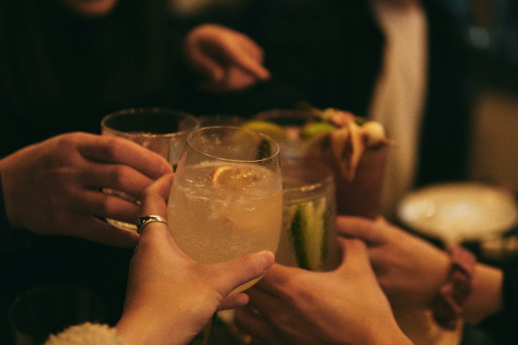 A variety of glasses with drinks being clinked together. 