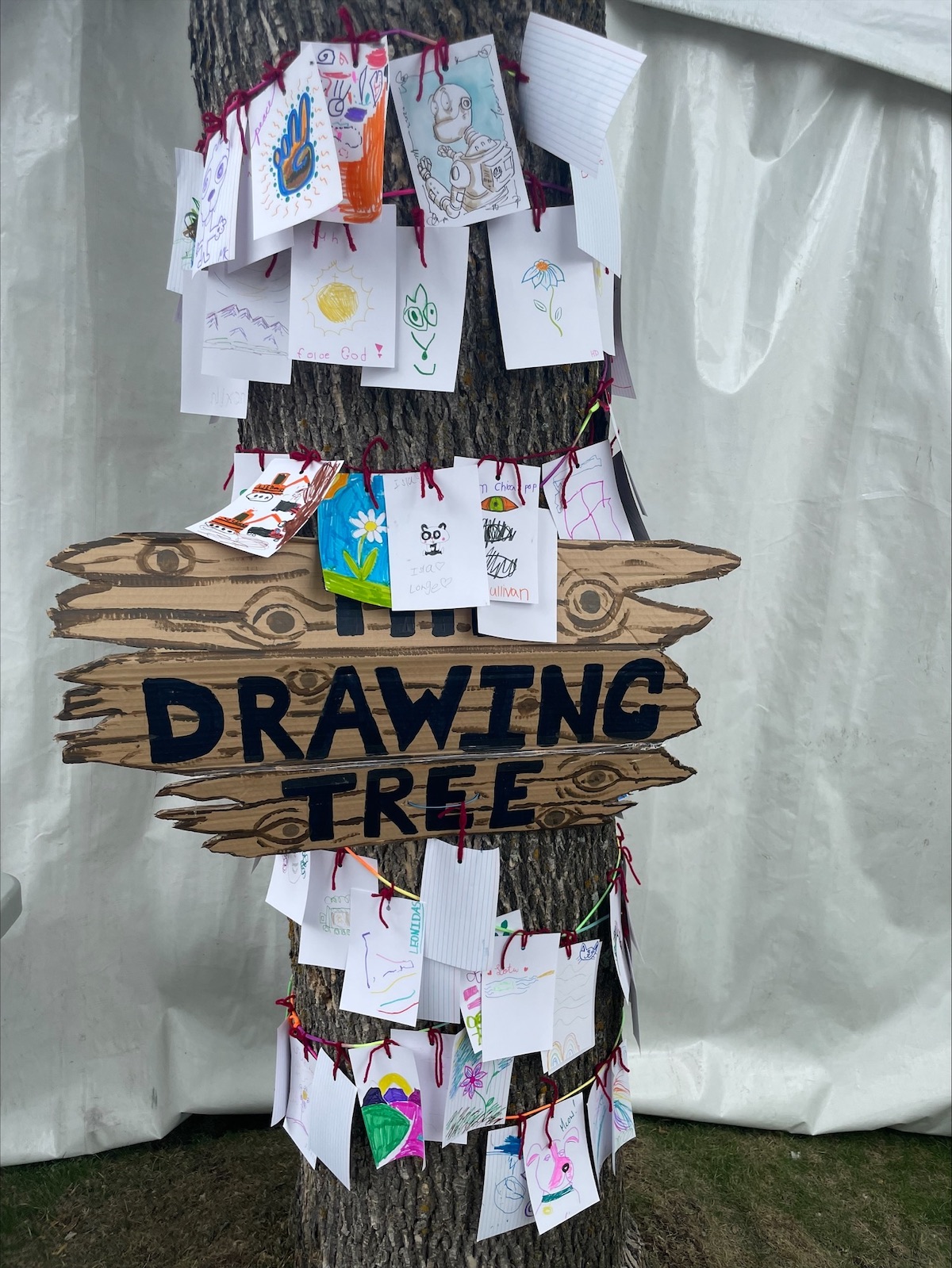 A tree with a sign Drawing Tree and small pictures hanging from it.