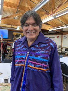Indigenous man, Ed Mandamin in a ribbon shirt smiling at camera.